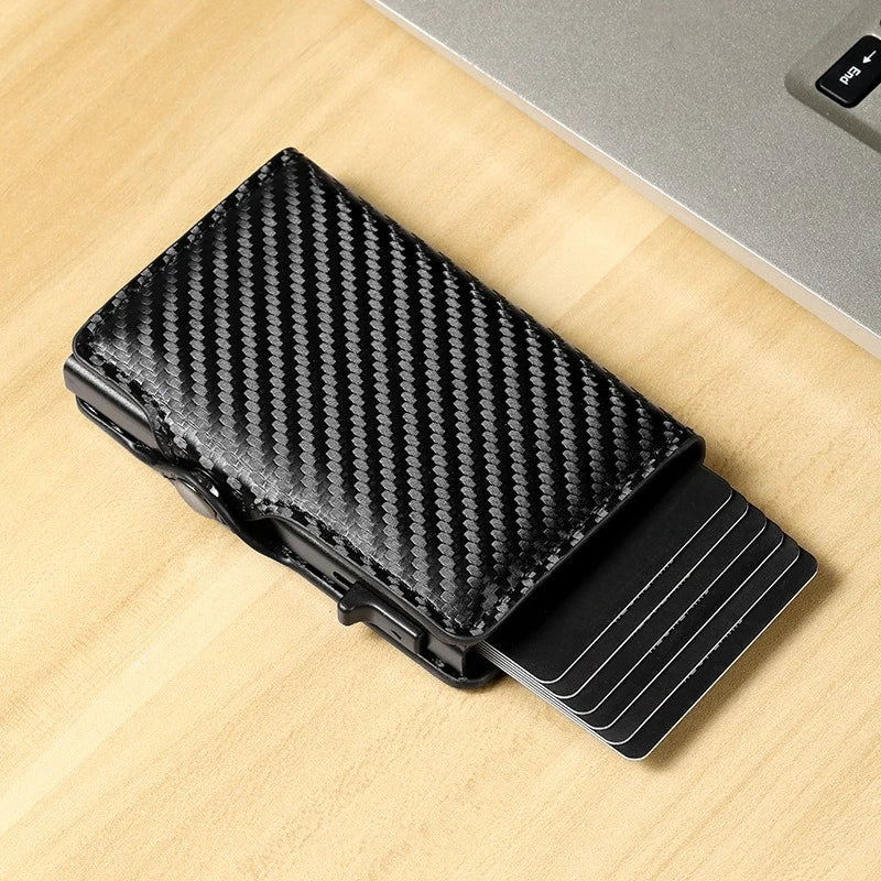 Black slim RFID-blocking carbon fiber card holder lying on a light wooden surface.