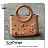 A round, tan PVC handbag with a handle and decorative butterfly holes on the surface.