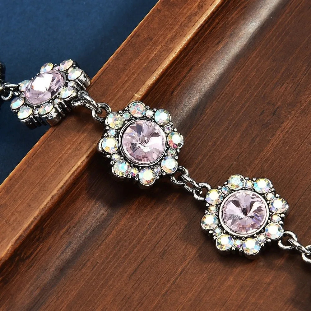 Silver crystal petal keychain featuring pink gemstone and rhinestone charms on a leather background