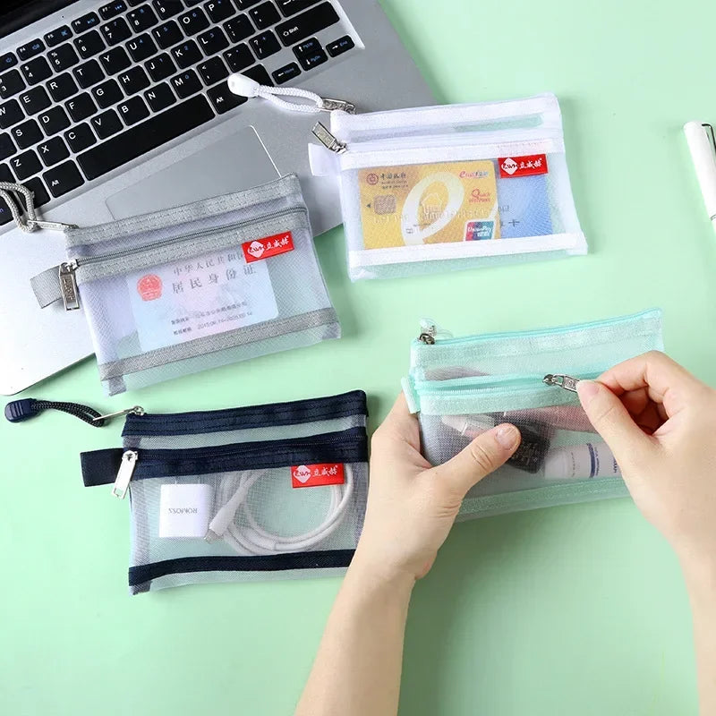 A hand is opening a clear zippered pouch containing various cards and coins, next to other similar pouches.