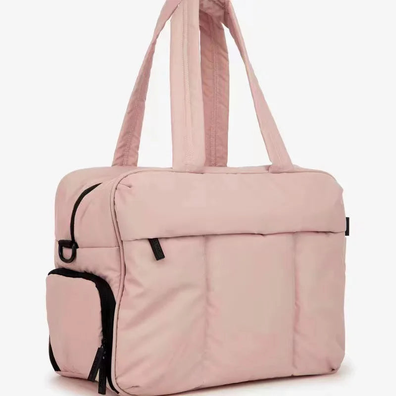A light pink large capacity women's travel duffle bag with pink fabric and black trim.