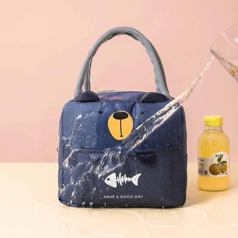 A dark blue insulated lunch bag with a handle is shown being filled with water, featuring a fish design and the text Have a G