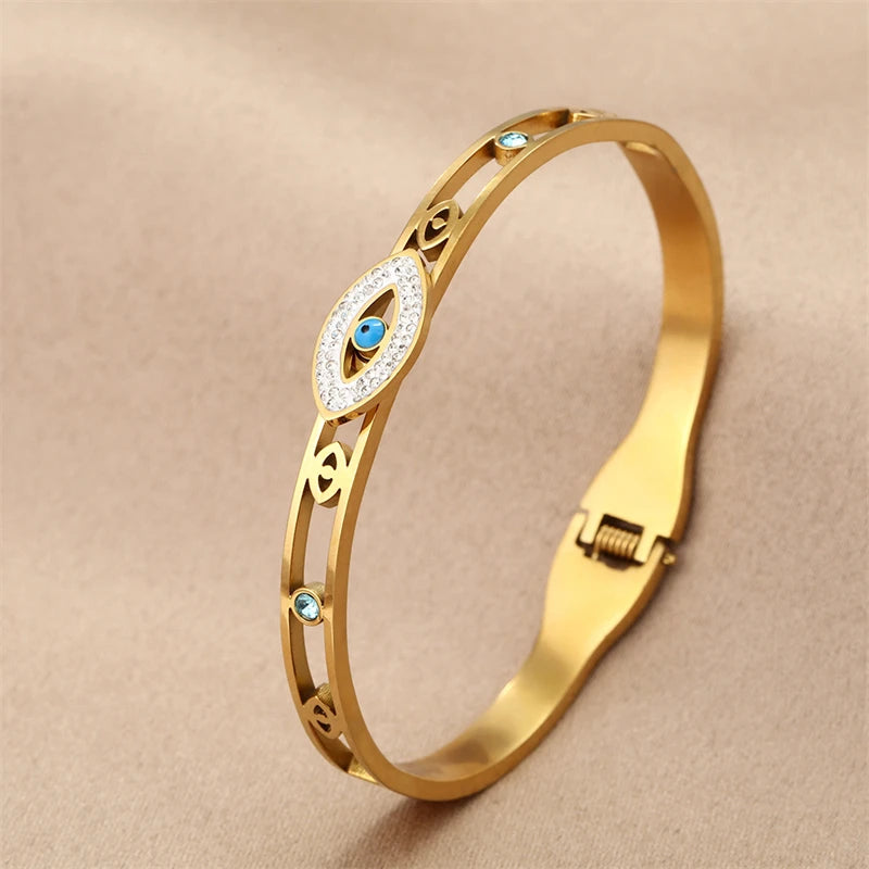 Gold cuff bracelet featuring an evil eye crystal design with blue accents.