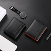 A black RFID-blocking bi-fold wallet with a carbon fiber texture is shown next to a wristwatch and a white smartphone.