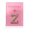 A pink leather passport holder with a gold initial Z and a pink airplane design.