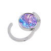 Silver folding table bag hook with a round, iridescent marble-like gemstone charm.