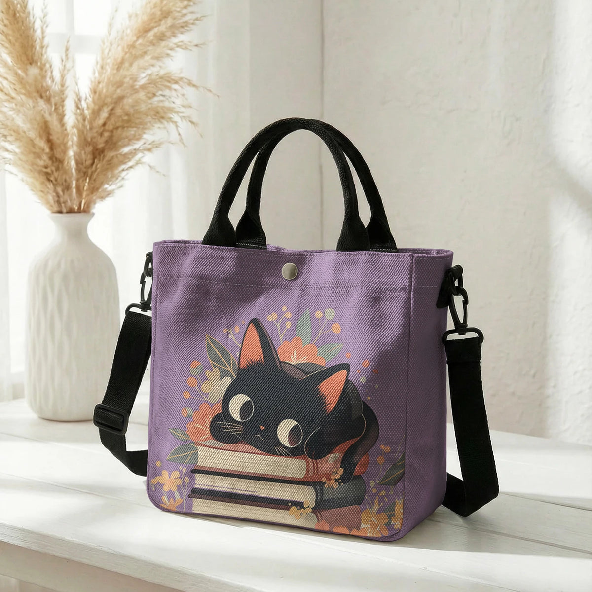 Lila Tasche mit Blumenkattenmuster und schwarzen Riemen auf weißem Untergrund.