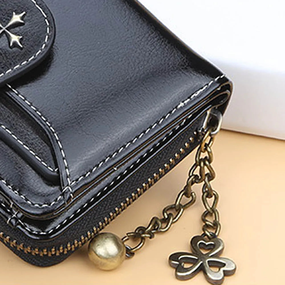 A black PU leather compact wallet with a zipper and gold chain is shown on a light background.