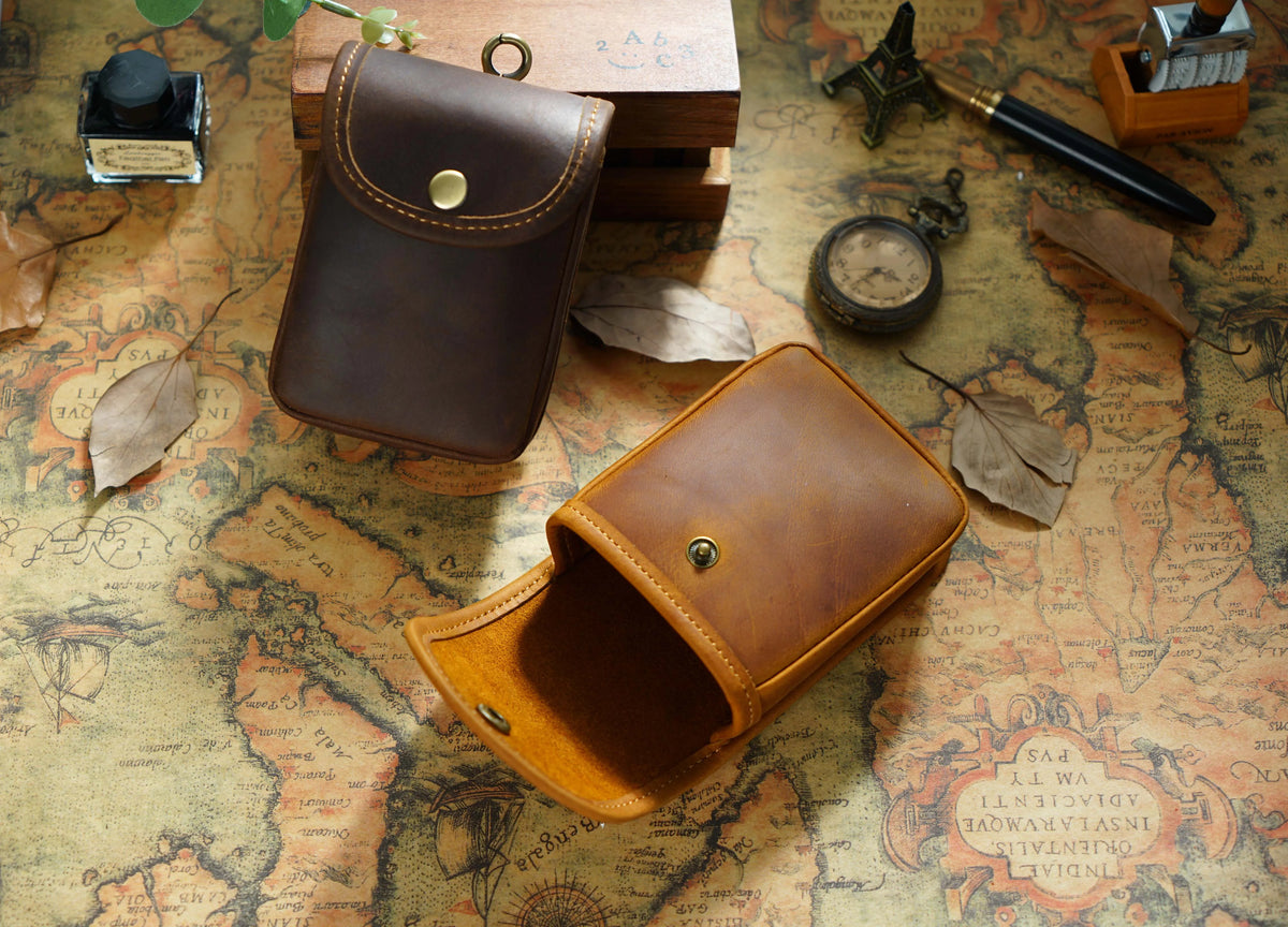 A brown leather multi-functional waist bag is shown open on an aged map background with various antique items.