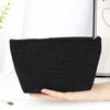 A black corduroy makeup organizer bag with an octagonal design is held in a hand.