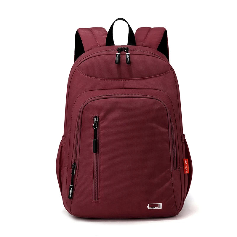 A maroon fashion commuter daypack for women with black accents and a zippered compartment.