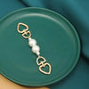 Gold metal purse chain strap with pearl beads displayed on a teal ceramic plate.