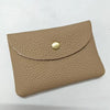 A tan genuine leather card holder with a stitched edge and a round brass-colored stud closure.