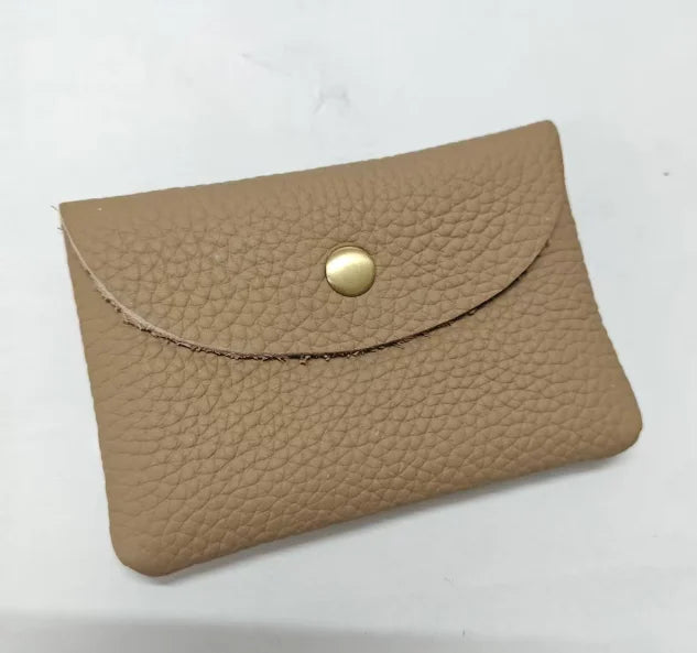 A tan genuine leather card holder with a stitched edge and a round brass-colored stud closure.