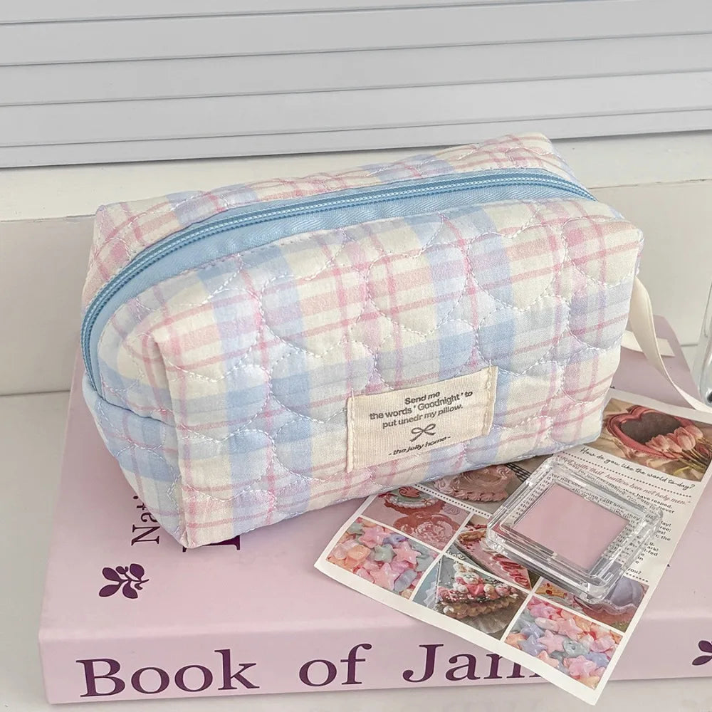 A light blue and pink quilted cosmetic bag resting on a pink box with a book title.