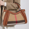 Caramel karierte Kuhfell-Tasche, getragen von einer Person in einem beige Jacke.