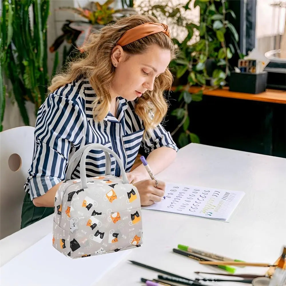 Une femme tient une sacoche de déjeuner en tissu Oxford réutilisable à motif sur une table blanche.