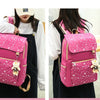 A pink sparkly canvas student backpack with a bear charm worn by a woman.