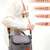 A person wearing a white sweater is carrying a gray insulated reusable lunch bag with a brown strap.