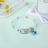 A white glow-in-the-dark pet collar with blue paw prints is displayed on a light green surface.