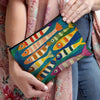 Une main tient un sac cosmétique vintage coloré avec des poissons peints de diverses couleurs vives.