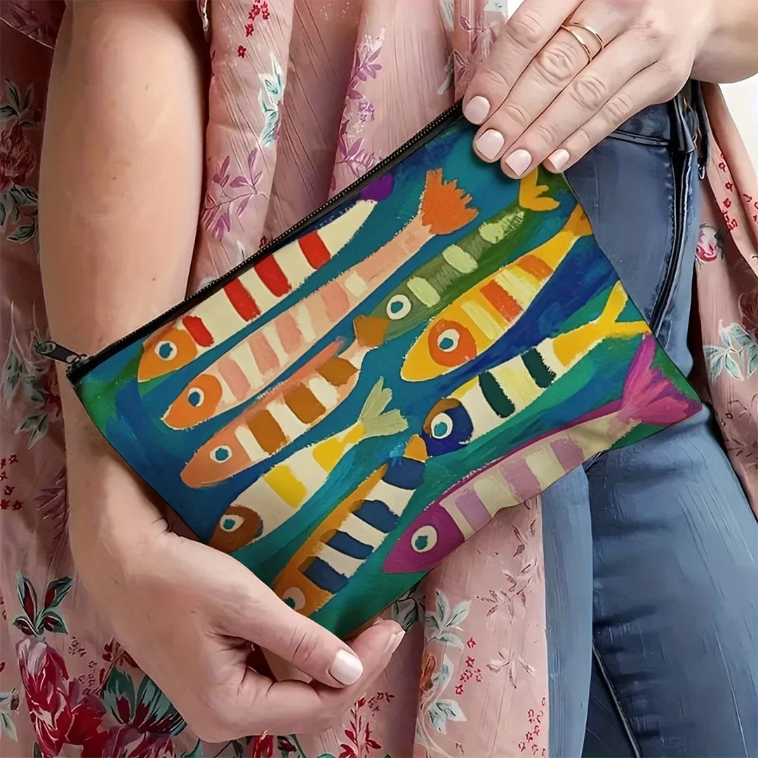Une main tient un sac cosmétique vintage coloré avec des poissons peints de diverses couleurs vives.