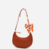 A brown leather bow bag with a chain strap extension and a floral fabric bow detail.