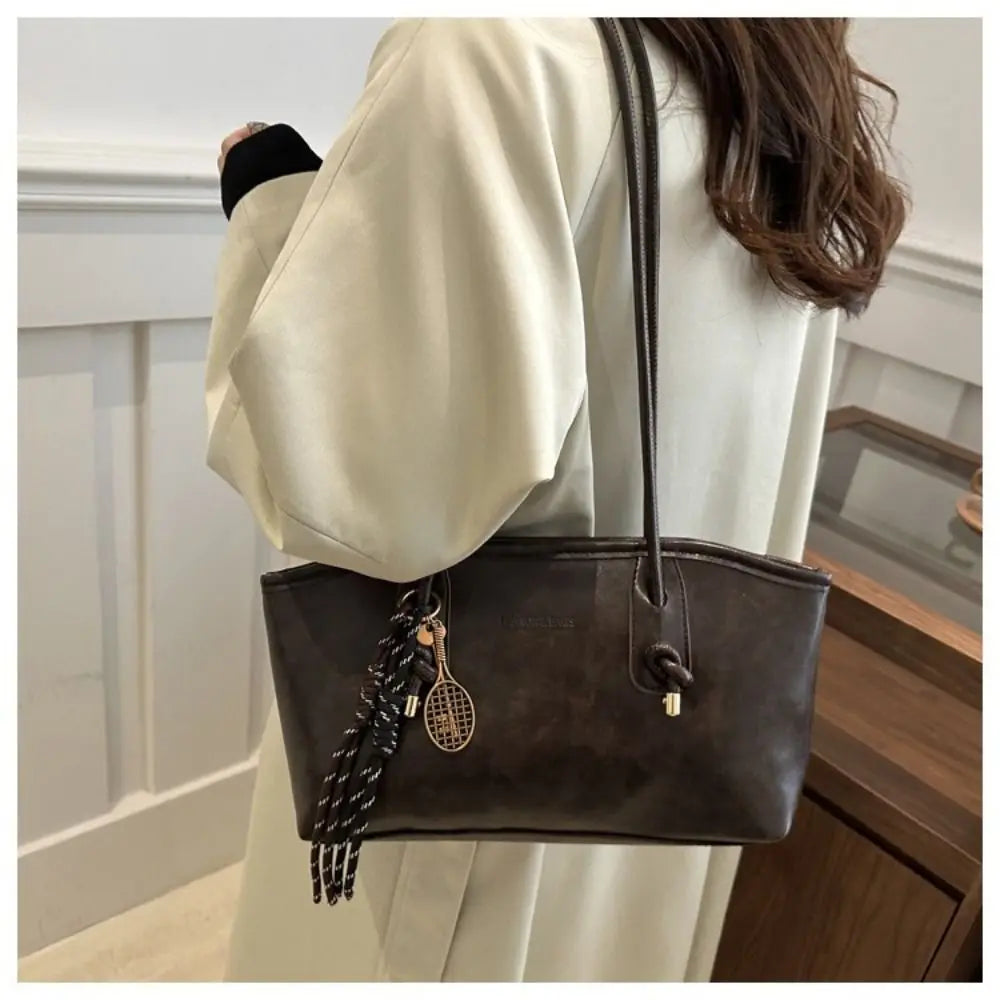A woman holds a large capacity brown PU leather tote bag with a black strap and gold hardware.