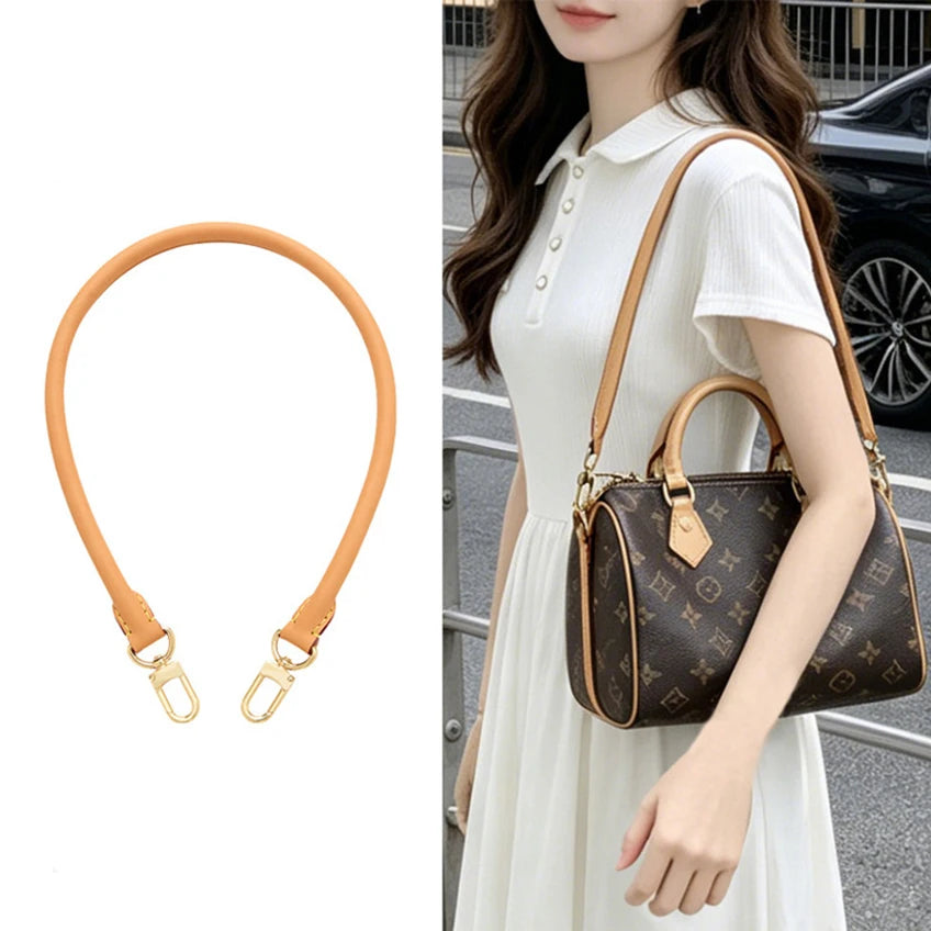A close-up of a tan adjustable synthetic leather bag strap attached to a handbag worn by a woman.