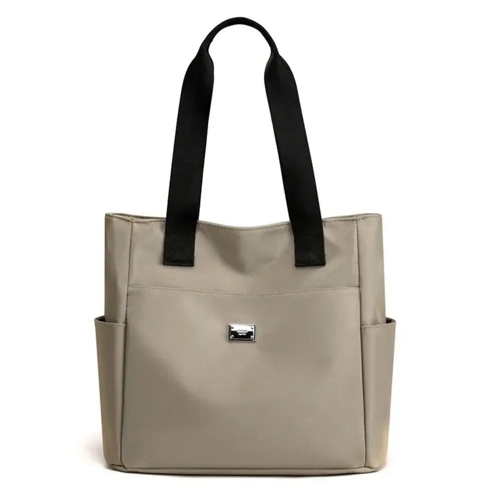 A beige nylon shoulder tote bag with black straps shown from the front.