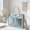 Un sac fourre-tout en velours côtelé bleu clair à pois roses accroché à un mur blanc.