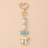 Gold pearl bow heart keychain with a blue gemstone detail