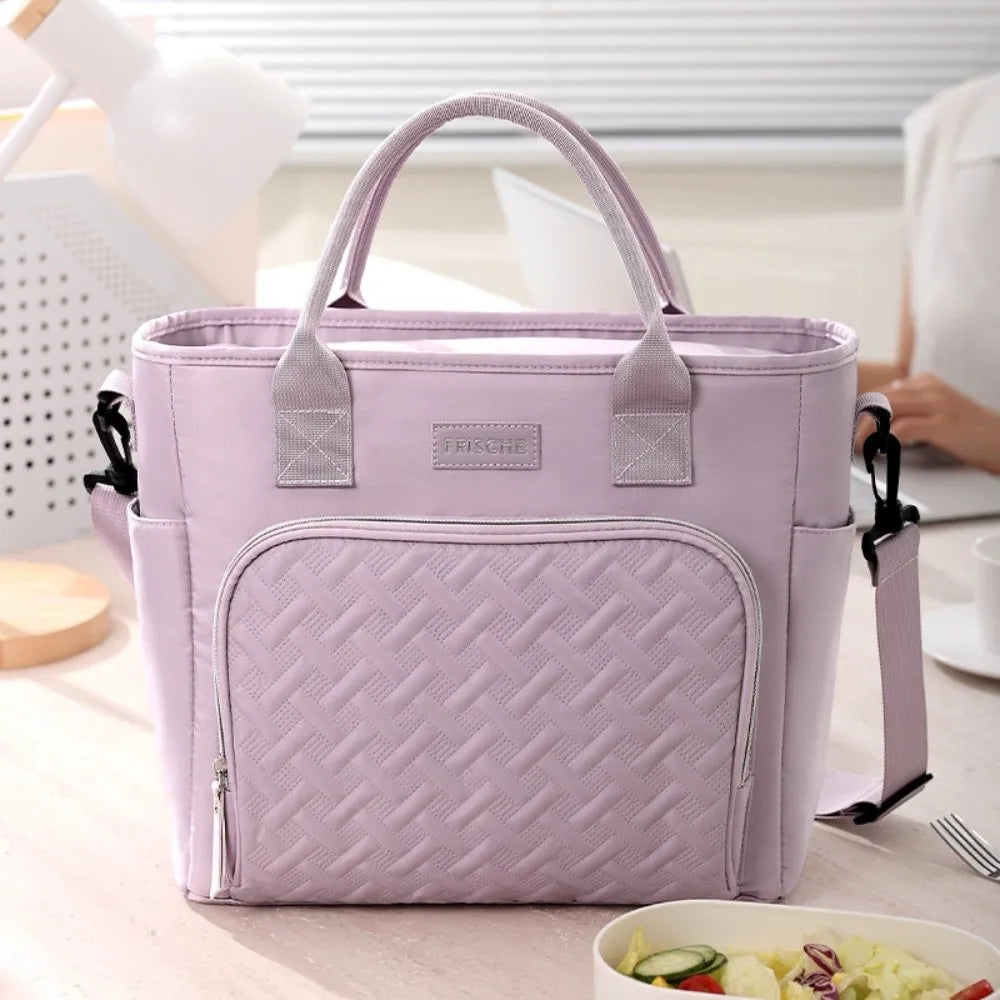A light purple insulated lunch bag with a quilted texture and handles is shown on a wooden surface.