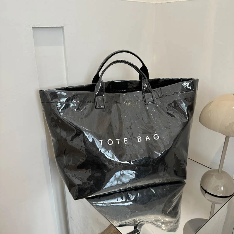 Una bolsa de tela de PVC negra y minimalista colgada contra una pared blanca.