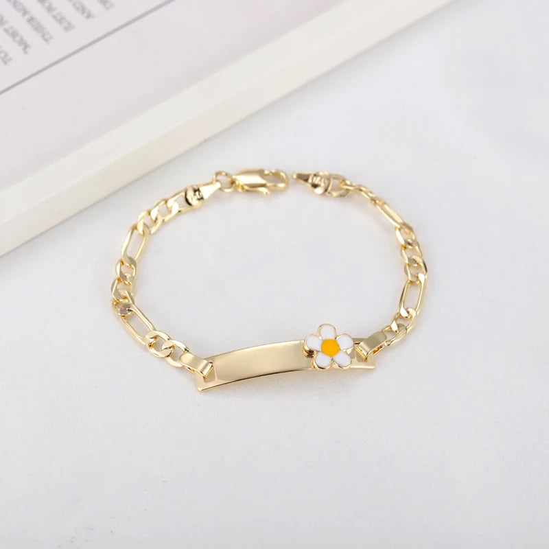 A gold-colored chain bracelet with a white and orange flower charm resting on a white background.