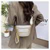 A woman is wearing a beige blazer and carrying a silver and gold rivet waist bag crossbody.