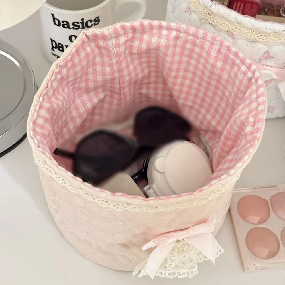 Cesta de tela de acolchado rosa con forma de corazón, llena de cosméticos redondos blancos y oscuros.