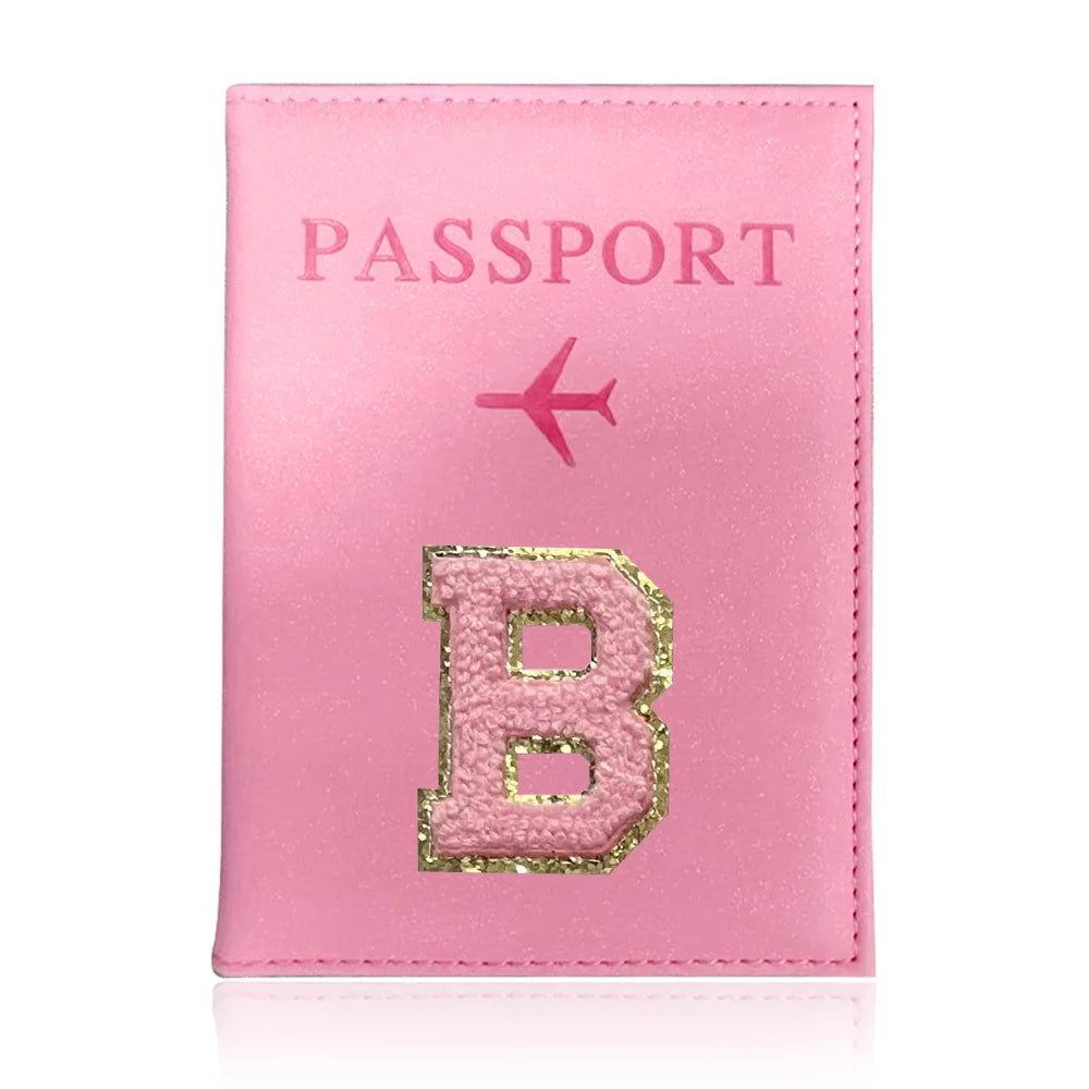 A pink leather passport holder with a gold embossed letter B and a pink airplane symbol.