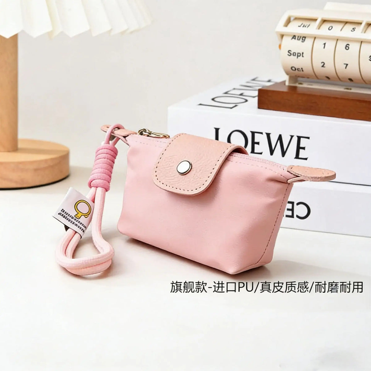 A pink compact coin purse made of nylon and faux leather with a pink braided keychain strap resting on a white surface.