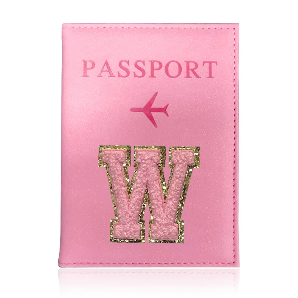 A pink leather passport holder with the word W embossed in glitter and a pink airplane design.