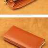 A close-up of a tan leather zipper wallet resting on a textured brown surface.