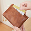 A hand holds a brown leather card holder wallet with a gold zipper and a yellow card inside.