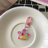 A pink resin flower keychain hanging over a white ceramic plate.