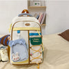 A beige and white campus backpack with blue accents and a brown strap resting on a light-colored surface.
