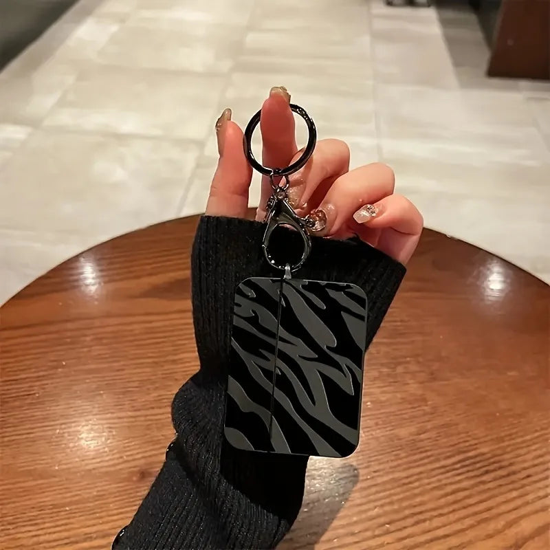 Une main tient une coque de protection à motif zèbre noir pour AirPods Pro.