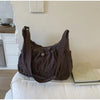 A dark brown plaid nylon drawstring tote bag resting on a white surface next to a book.