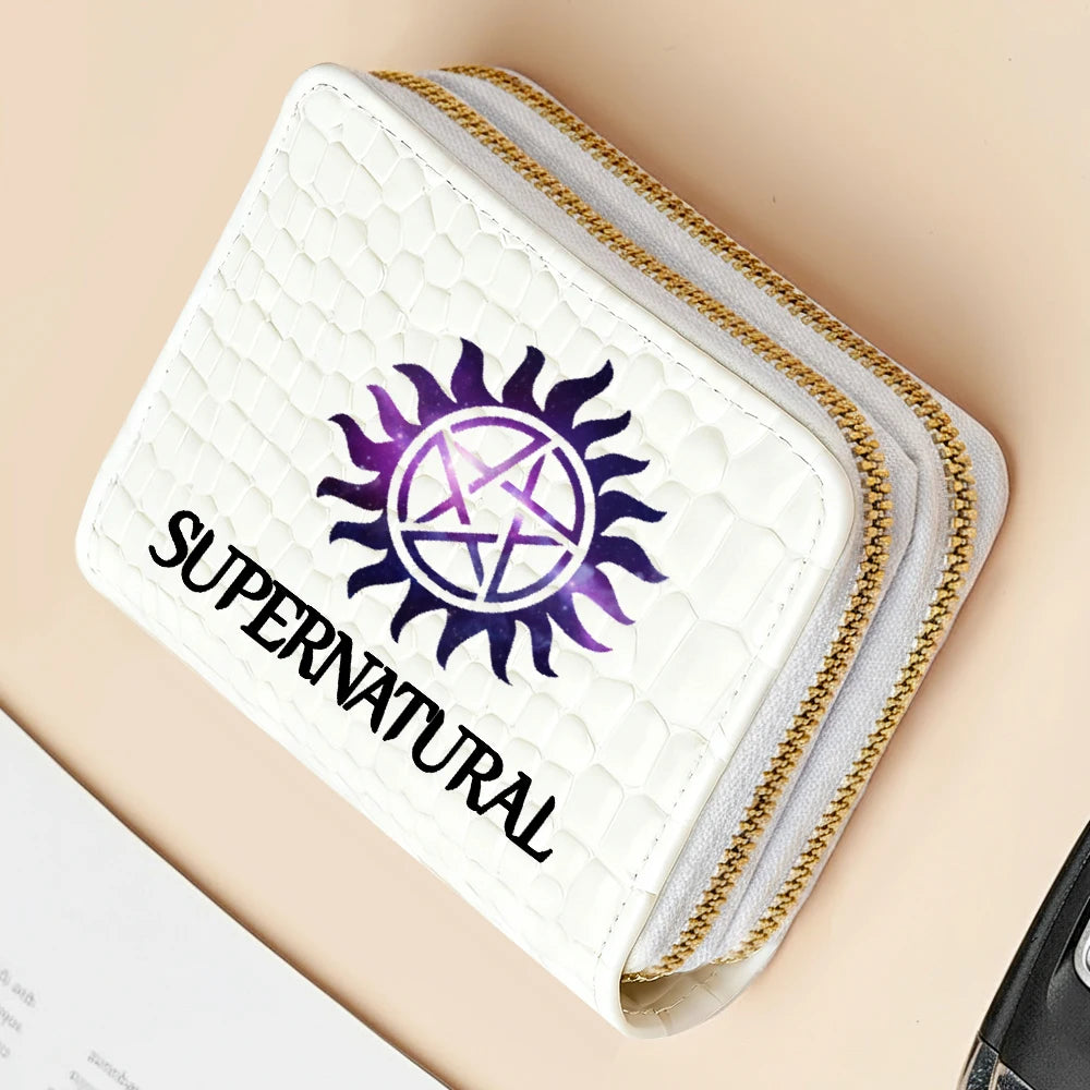 A white quilted wallet with gold stitching and a purple sun symbol on the cover.