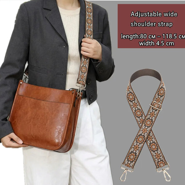 A brown leather shoulder bag with an adjustable textile strap is shown being worn by a person.