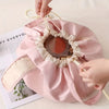 A pink satin makeup organizer bag with a decorative opening is being held by a hand.