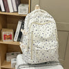 Una mochila blanca con estampado floral azul y múltiples bolsillos sobre una maleta.